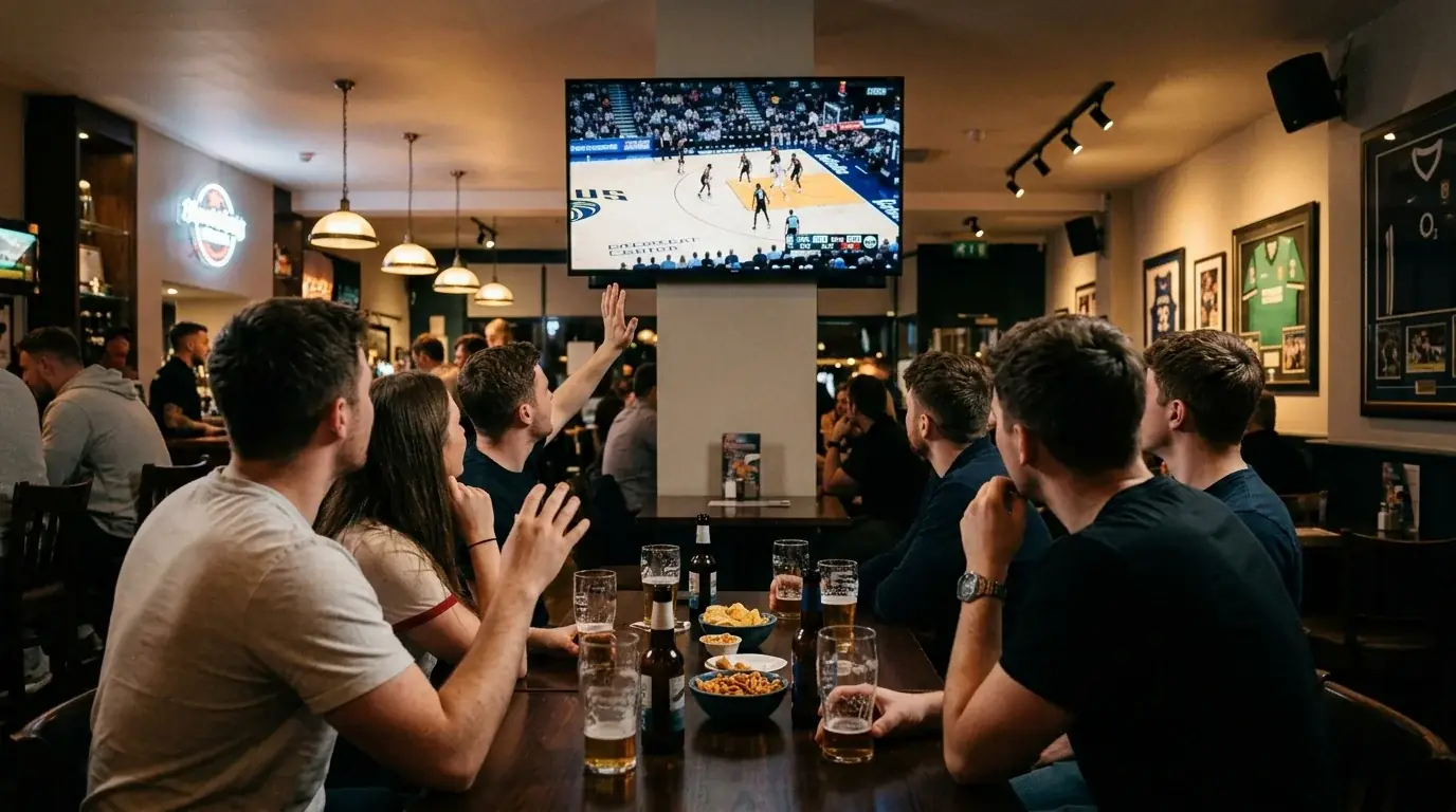 Fans watching an NBA game on a large screen in a UK sports pub